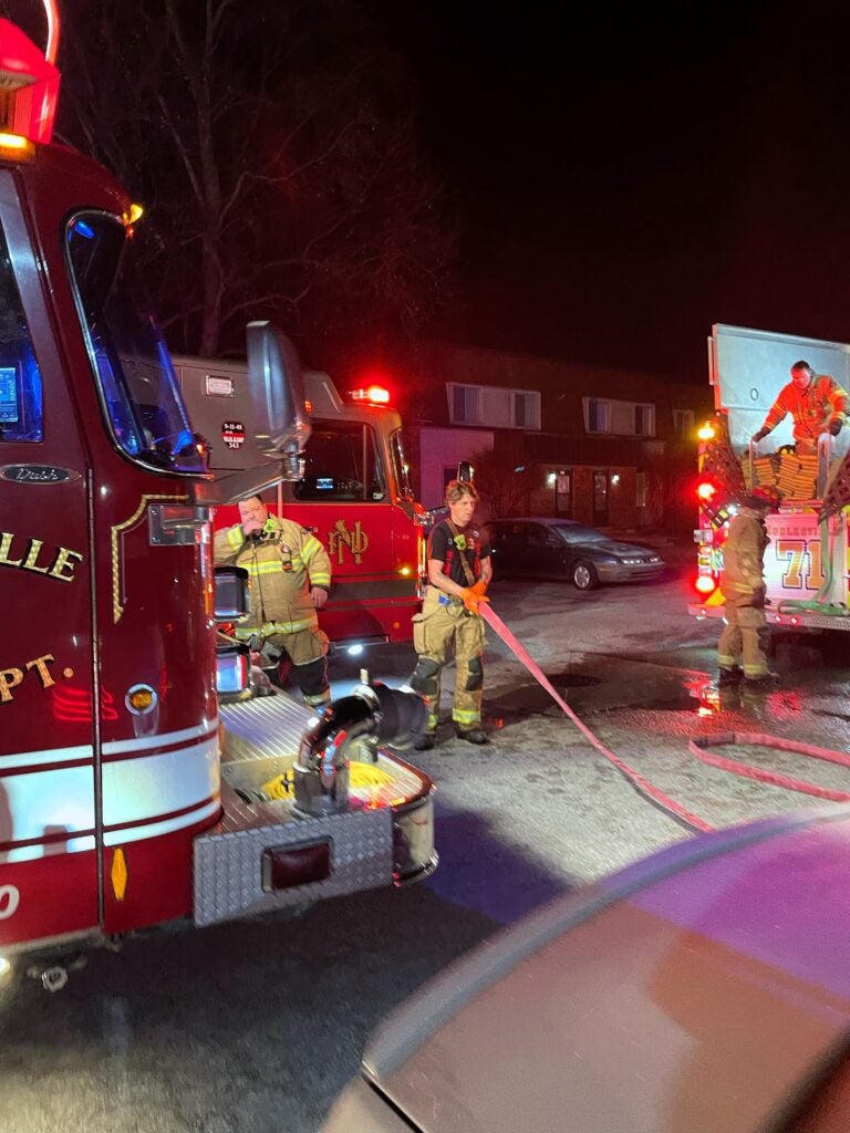 Noblesville firefighters stand next to two fire engines at the scene of an apartment fire at Noble Manor on Dec. 15, 2023. (Provided Photo/NFD)