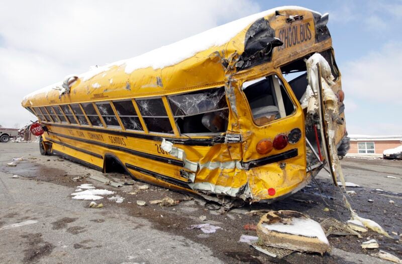 A school bus is lodged in Henryville High School parking lot after damaged by Friday's tornado in Henryville, Ind., Monday, March 5, 2012.