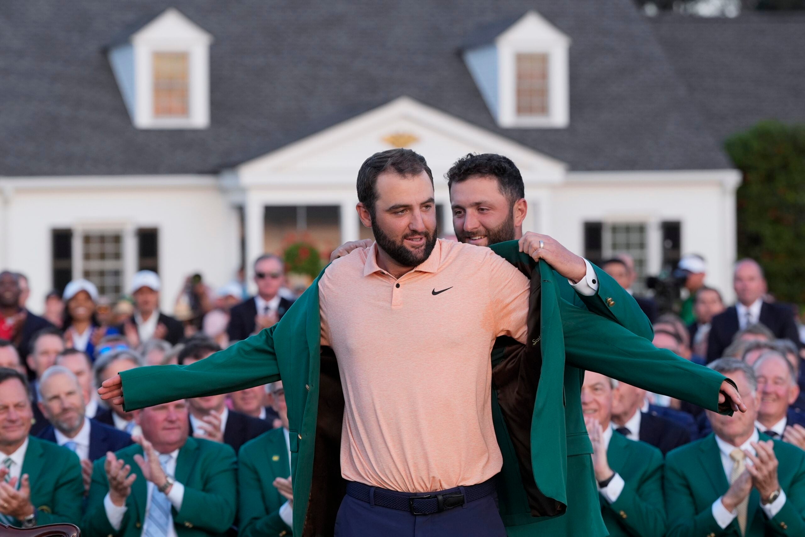 Jon Rahm, of Spain, puts the green jacket on winner Scottie Scheffler after the Masters golf tournament at Augusta National Golf Club Sunday, April 14, 2024, in Augusta, Ga. (AP Photo/David J. Phillip)